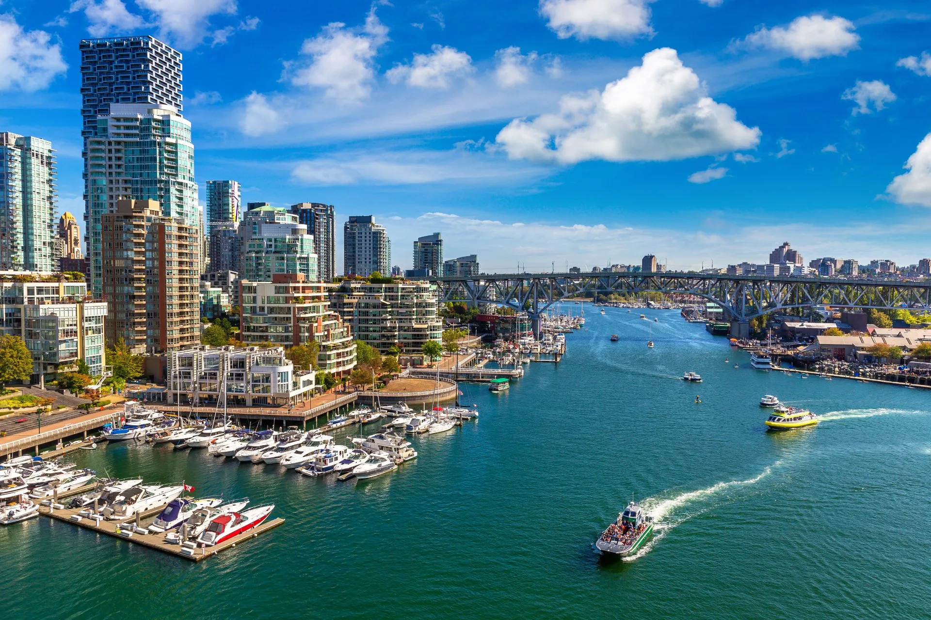 Aerial view of Vancouver's False Creek marina and waterfront towers under a blue sky