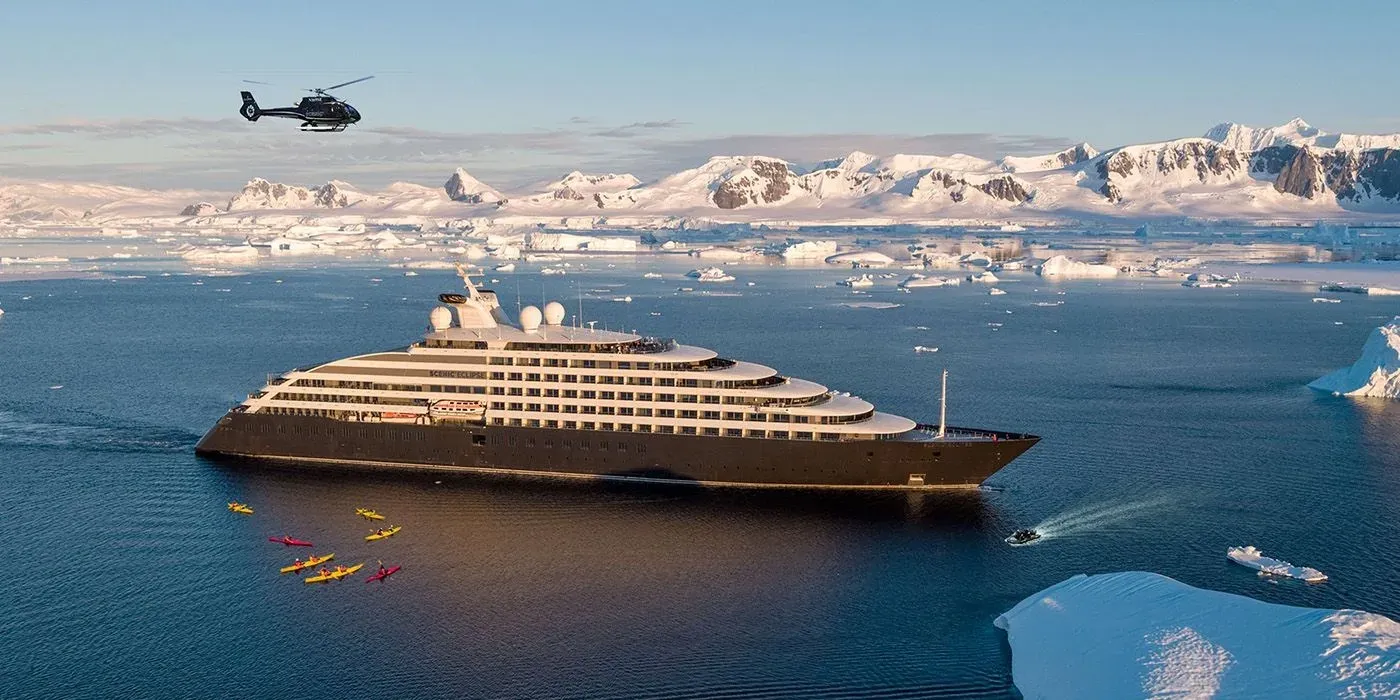 Scenic Eclipse in Antarctic waters with kayakers alongside and its helicopter overhead